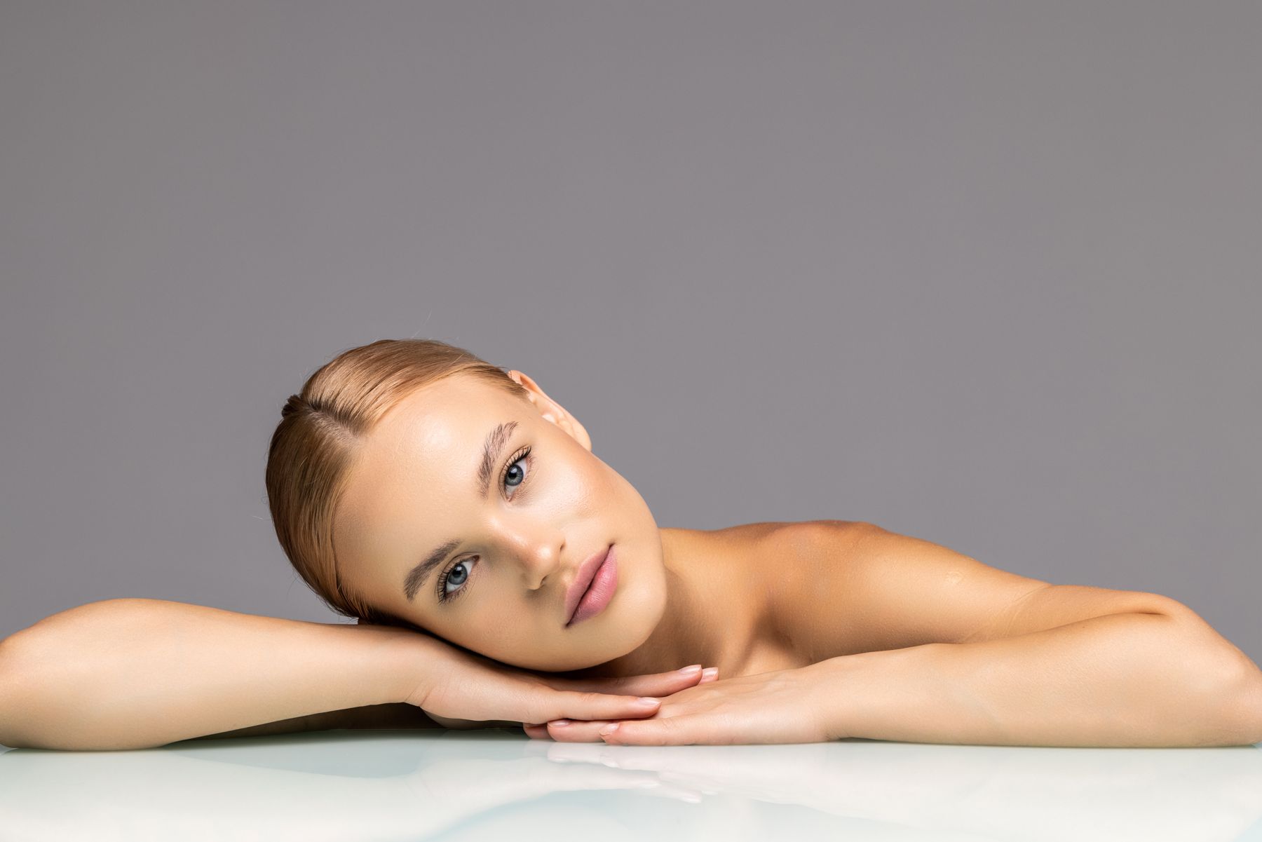 Portrait of a woman with smooth, natural-looking skin resting her head on her arms